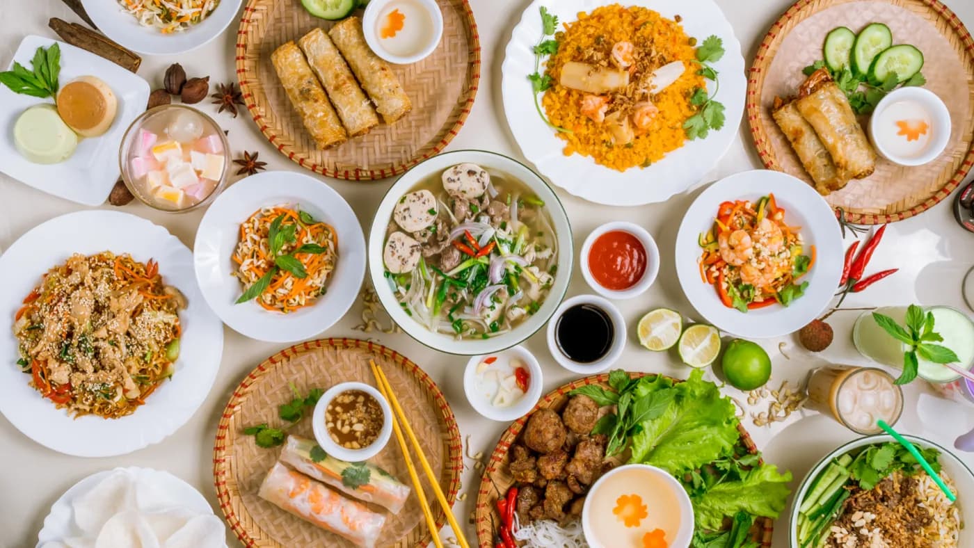 Overhead spread of Pho 8 favorites including pho, fried rice, egg rolls, grilled meat and boba