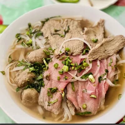 Combination beef pho with noodles, onion and fresh herbs