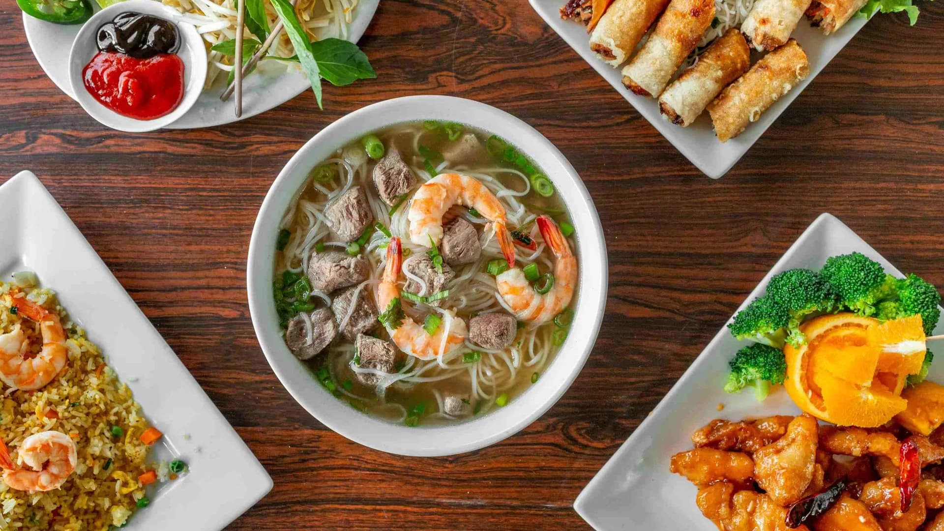 Pho 8 table spread with combination pho, egg rolls, fried rice and Vietnamese and Chinese dishes